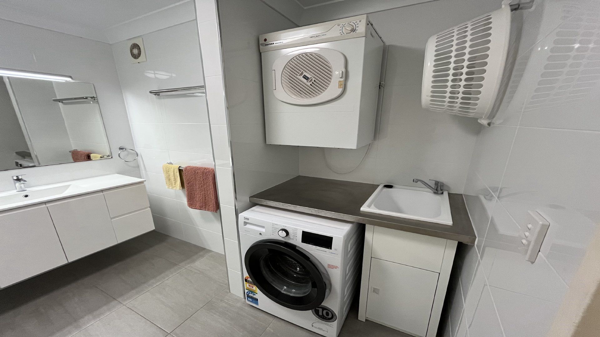 A modern bathroom with a built-in washing machine, a sink, and a mirror.