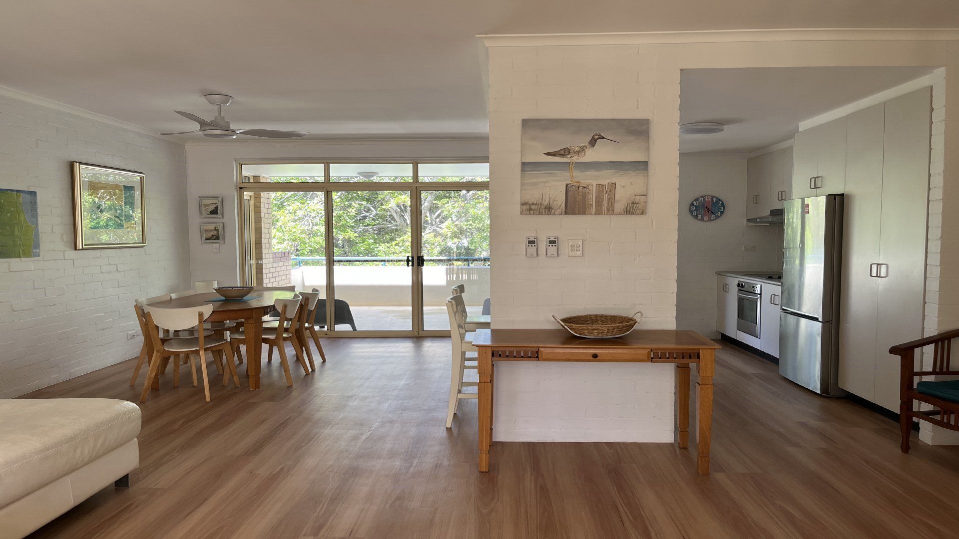 A modern living space with a dining area, kitchen, and a large sliding glass door leading to a balcony.