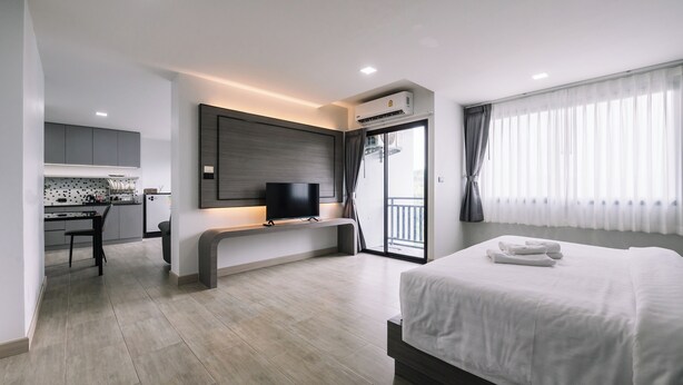 A modern hotel room with a large bed, a TV, a desk, and a balcony with curtains. - Aston Residence hatyai (Hat Yai)