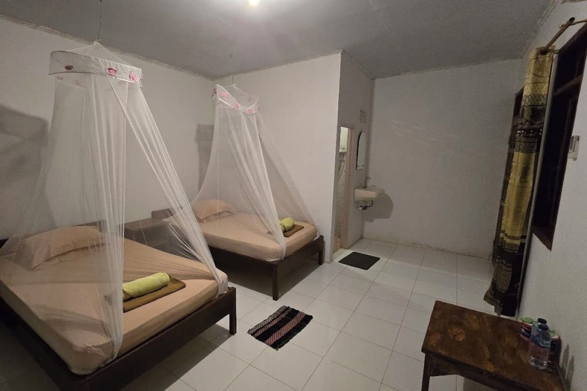 A room with two beds, each with a canopy, a small table, and a mirror.