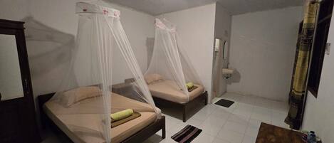 A room with two beds, each with a canopy, a small table, and a mirror.