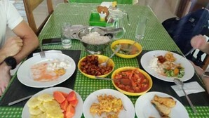 Une table dressée avec divers plats, notamment du riz, des légumes et des aliments frits, sur une nappe à carreaux verts.
