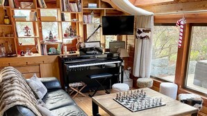 A cozy living room with a piano, a large bookshelf, a television, and a chessboard. - Rustic Mountain Chalet with Jacuzzi (Formiguères)
