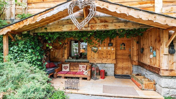 A wooden cabin with a covered porch, a bench, and a heart-shaped decoration. - Rustic Mountain Chalet with Jacuzzi (Formiguères)