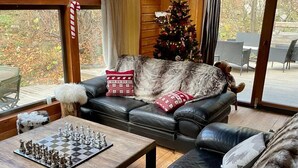 A cozy living room with a chessboard, leather sofas, a Christmas tree, and a wooden ceiling. - Rustic Mountain Chalet with Jacuzzi (Formiguères)