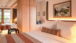 Une chambre d’hôtel avec deux lits, une armoire en bois, un tableau au mur et une petite table avec une bouilloire.