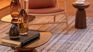 Une chambre moderne avec un fauteuil en cuir, une petite table ronde ornée d’un vase, d’un livre et d’un objet décoratif.