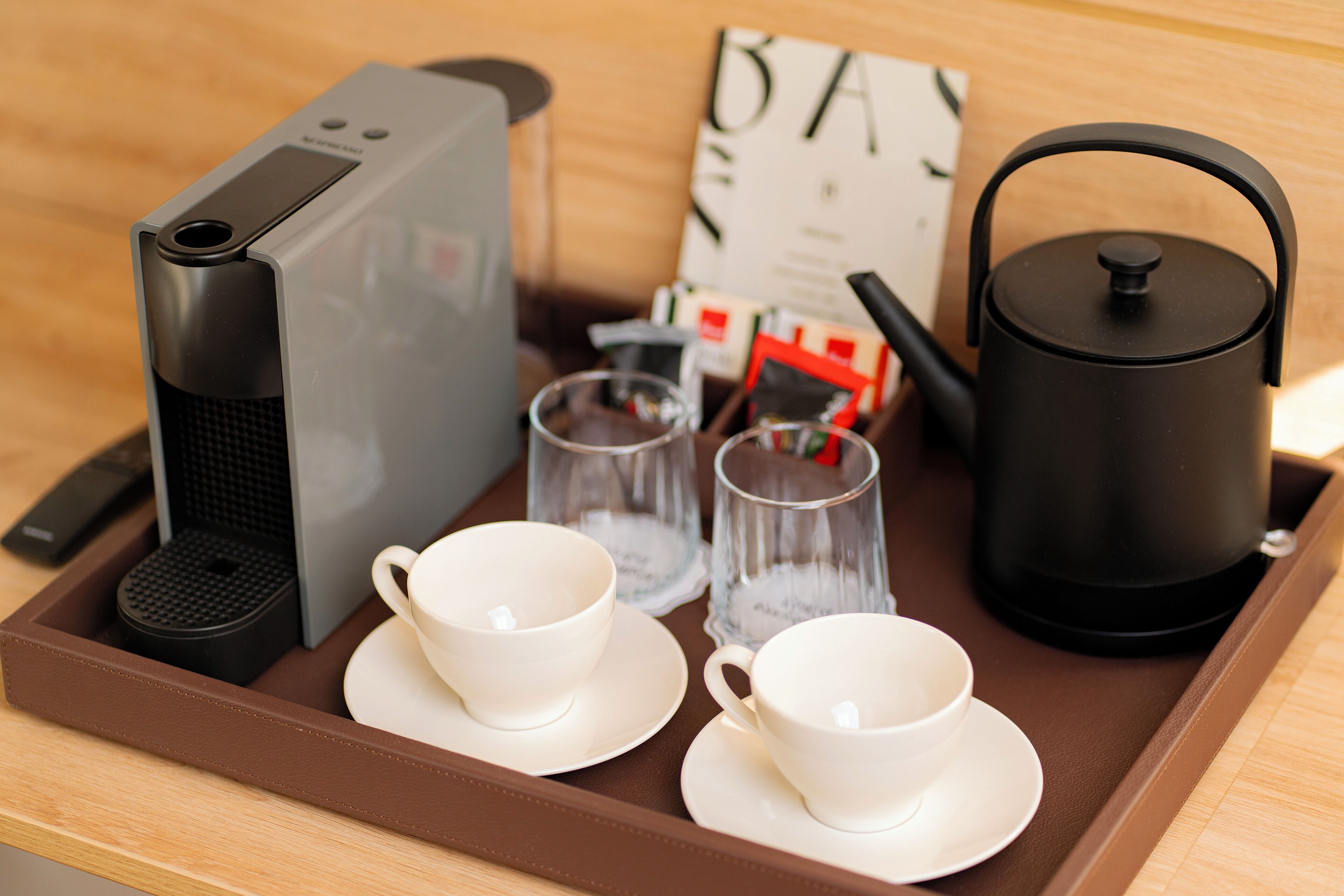 A tray with a coffee maker, two cups, two glasses, a kettle, and a menu.