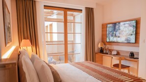 Une chambre d’hôtel équipée d’un lit, d’un bureau, d’une chaise, d’une télévision et offrant une vue sur l’extérieur.