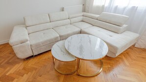 Una sala de estar moderna con un sofá modular, una mesa de centro de mármol y suelo de madera.