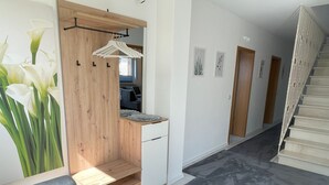 A hallway with a wooden bench, a small wooden table, and a staircase. - 152 m² vacation apartment Quiet location on the edge of the village Overlooking the Rhine Valley Opposite the Loreley (Sankt Goar)