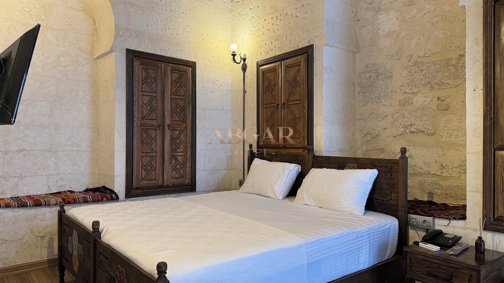 Un dormitorio con cama de madera, dos armarios, una mesita de noche y una lámpara de pared.