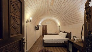 Una camera da letto con soffitto in mattoni, un letto, un comodino, una lampada e un tappeto decorato.