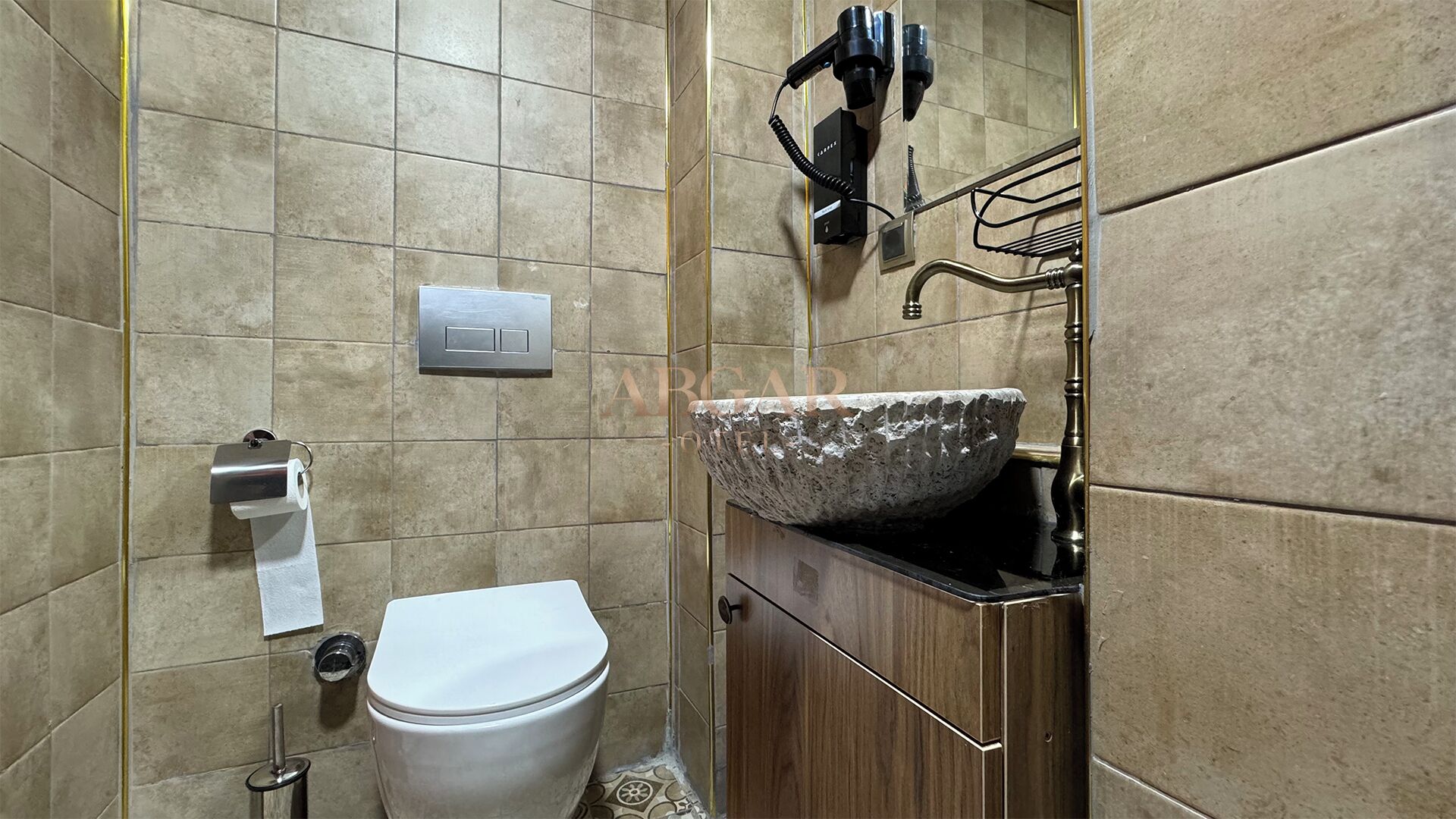 Een badkamer met een toilet, een wastafel met een stenen wasbak en een handdoekdispenser.