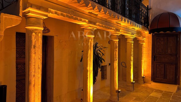 Un edificio con una serie di colonne e un'apertura, illuminato da luci calde.