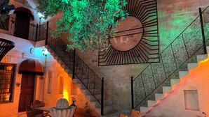 Una scala con ringhiere in metallo decorate, una fontana e un albero con verdeggiante chioma.