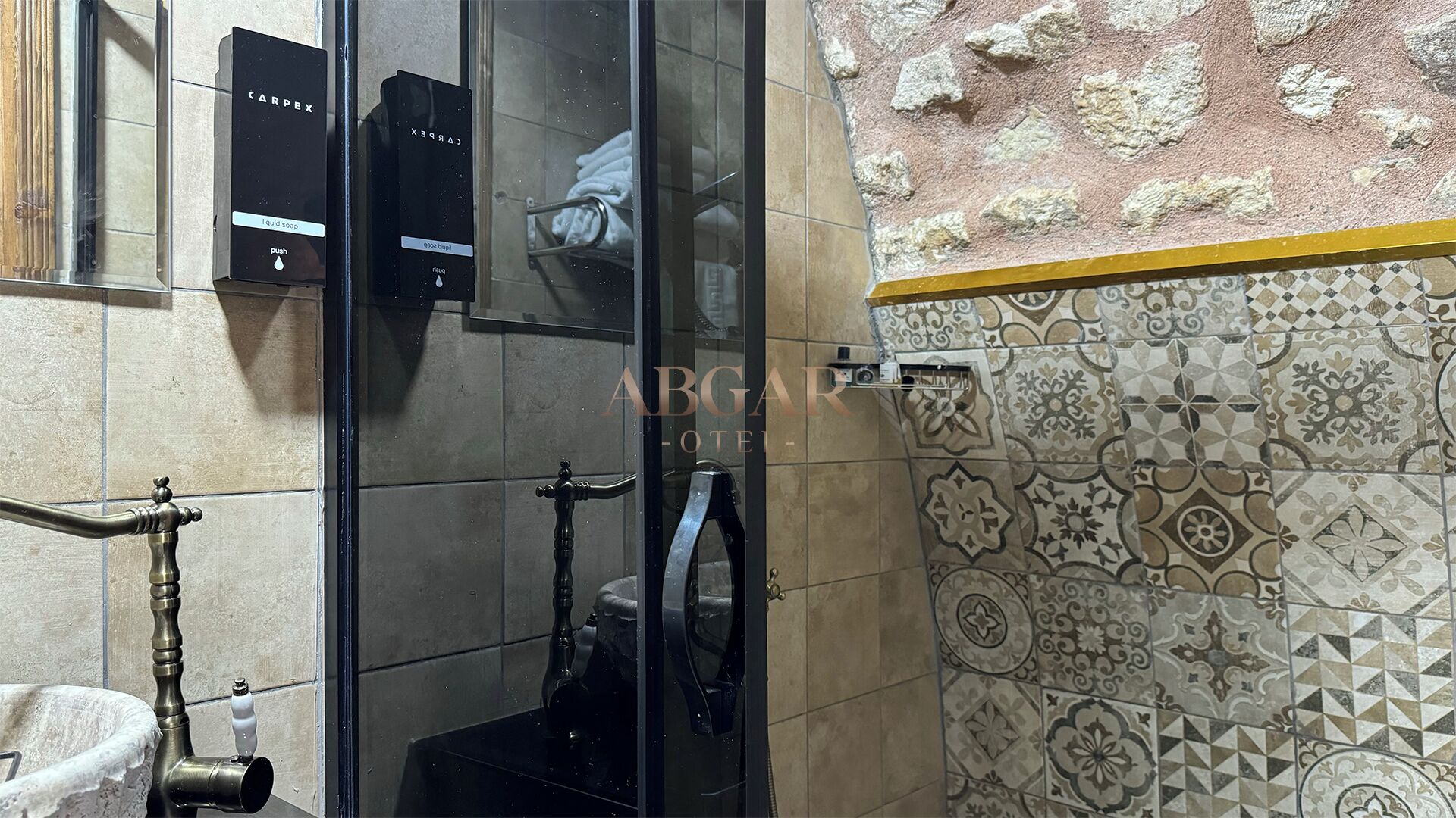Une salle de bain avec une douche à parois de verre, un distributeur de savon à bouton-poussoir et un porte-serviettes.