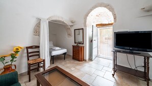 A room with a bed, a TV, a wooden cabinet, and a window with a view. - Il Trullo di Nonna Ratuccia by Rentbeat (Ostuni)