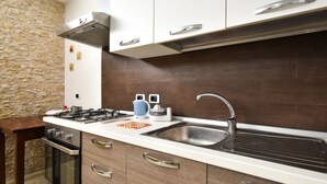 A modern kitchen with a gas stove, oven, and stainless steel sink. - Casa Carlà by Rentbeat (Surbo)