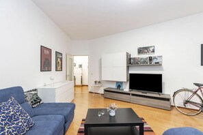 A modern living room with a sofa, coffee table, TV, and a bicycle. - Casa Beira e Jambo by Rentbeat (Bari)