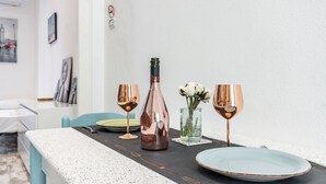 Une table à manger avec une bouteille, deux verres et un vase rempli de fleurs.