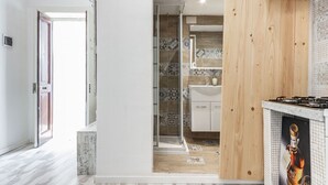 Une cuisine moderne avec des meubles en bois, un pare-feu en carrelage et une cabine de douche en verre.