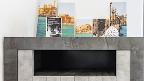 Une cheminée au design moderne, un mur orné de tableaux encadrés et un mur à la texture évoquant le marbre.