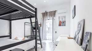 Une chambre d’hôtel moderne avec un lit superposé, un bureau, une grande fenêtre avec des rideaux et des œuvres d’art accrochées aux murs.