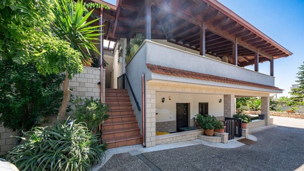 A two-story house with a covered porch, a brick staircase, and potted plants. - Apart Irene by Rentbeat (Ostuni)
