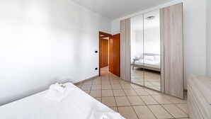 A modern hotel room with a bed, a wardrobe, and a bathroom visible through a mirror. - Apart Irene by Rentbeat (Ostuni)