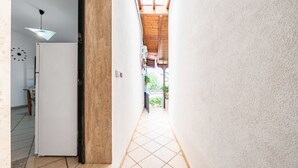 A narrow hallway with a tiled floor, a white wall, and a wooden ceiling. - Apart Irene by Rentbeat (Ostuni)