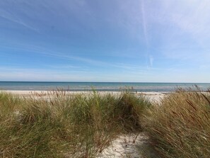 A beach with sand dunes and grass in the foreground, leading to the ocean. - "Auvo" - 200m from the sea by Interhome (Nexø)