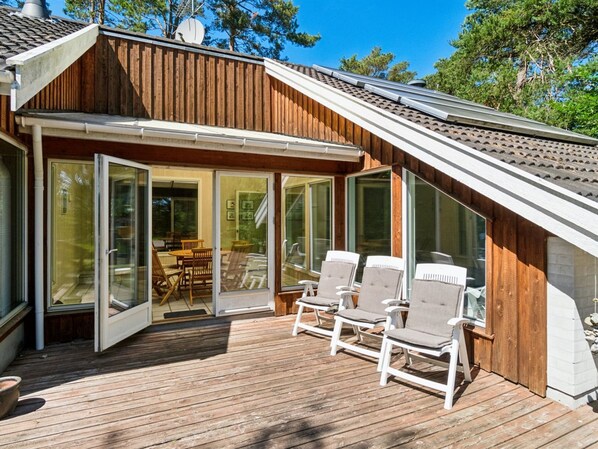 A wooden deck with outdoor seating and a glass-enclosed patio.