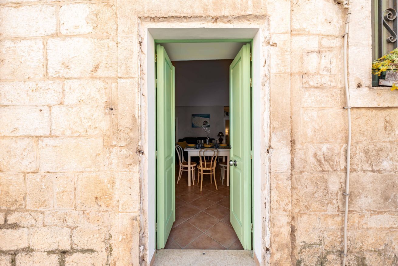 A stone building with a doorway leading to a dining area with a table and chairs.