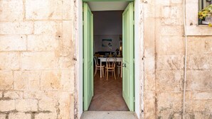 A stone building with a doorway leading to a dining area with a table and chairs. - Il Vico 113 Ostuni by Rentbeat (Casoria)