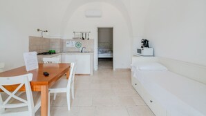 Een compacte kamer met een kitchenette, een eethoek en een bed.