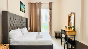 A bedroom with a large bed, a desk, a chair, a mirror, and a window with curtains. - OYO 1233 Home Elite 1 Residence Sports City, Dubai (Dubai)