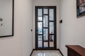 A hallway with a dark wooden door, a tiled floor, and a framed picture on the wall. - Casa dei Renai by Rentbeat (Signa)