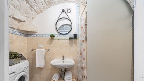 A compact bathroom with a washing machine, a sink, a mirror, and a shower curtain. - Il Vico 8 Ostuni by Rentbeat (Ostuni)