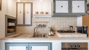 A kitchen with a sink, stove, cabinets, and a shelf with jars. - Il Vico 8 Ostuni by Rentbeat (Ostuni)