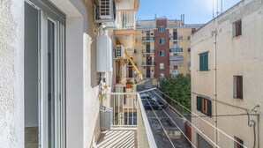 En smal stadsgata med byggnader, en balkong med ett räcke och en kran i bakgrunden.