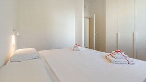 Ett hotellrum med en säng, en garderob och en dörr som leder till ett annat rum.