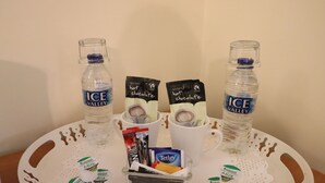 A tray with instant hot chocolate packets, a bottle of water, and a small container of tissues. - St George's Lodge (Woking)