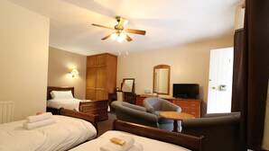 A hotel room with two beds, a desk, a chair, a television, and a ceiling fan. - St George's Lodge (Woking)
