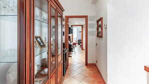 A hallway with a wooden cabinet, a tiled floor, and a door leading to another room. - Casa Giancarlo by Rentbeat (Roma)