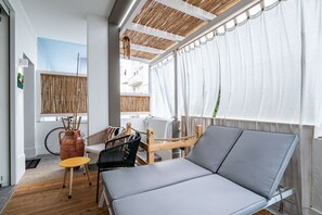 Aurinkoinen huone, jossa on puinen katto, pehmustettu sohva, pieni pöytä ja polkupyörä.