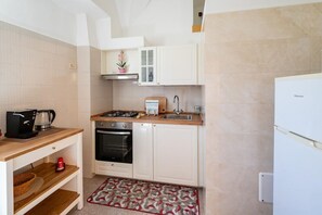 A compact kitchen with white cabinets, a built-in oven, a coffee maker, and a sink. - Casa Cenzina by Rentbeat (Locorotondo)