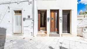 A building with three doors, a small entrance, and a staircase leading to the ground floor. - Casa Cenzina by Rentbeat (Locorotondo)