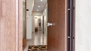 A hallway with a patterned rug, a wooden door, and a view into a room with a bed and a chair. - Casa Cenzina by Rentbeat (Locorotondo)