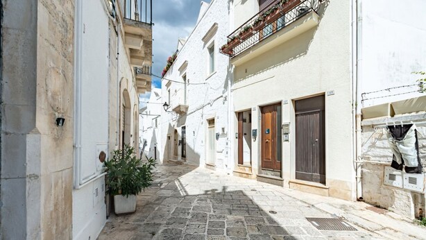 A narrow cobblestone street flanked by white buildings with balconies, doors, and windows. - Casa Cenzina by Rentbeat (Locorotondo)